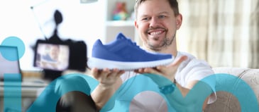 Man holds up blue sneaker in front of camera